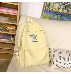 Detail shot of the cute yellow backpack featuring lovely puppy embroidery and side baseball keychain.