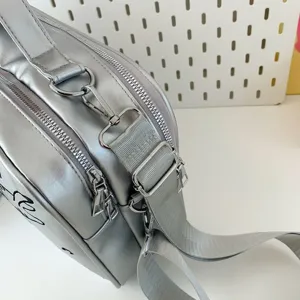 Detail view of silver metallic ita bag hardware, zippers, and adjustable shoulder straps.