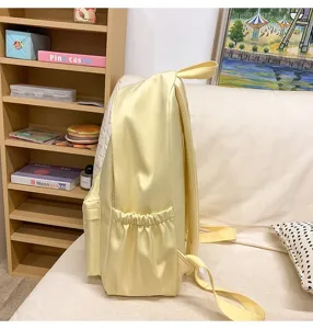 Solid color casual school backpack in light yellow with side pockets and simple design.
