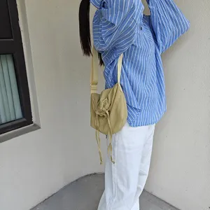 Outdoor detail view of a casual nylon dumpling crossbody bag with drawstring closure.