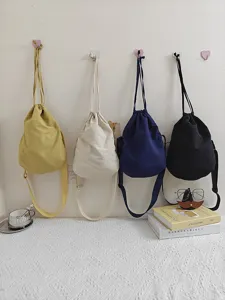 Detailed view of stylish nylon drawstring crossbody dumpling bags hanging on wall.