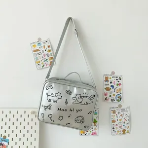Silver crossbody pain bag detail view, featuring cute cartoon dog and cat doodle prints.