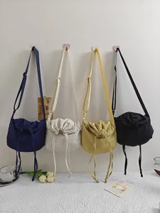 Detailed view of multi-color nylon crossbody dumpling bags hanging on wall display.