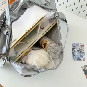 Silver ita bag detail showing spacious interior capacity with cute doll and notebooks inside.