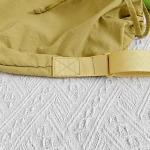Close-up detail of yellow nylon crossbody bag strap and drawstring design, high quality.
