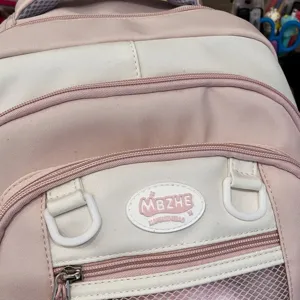 Rucksack Detailansicht zeigt rosa weißes Design mit Fronttasche und coolem Markenlogo Patch.