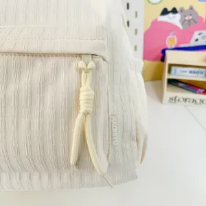 Gros plan détaillé de la poche avant du sac à dos texturé avec cordon décoratif.