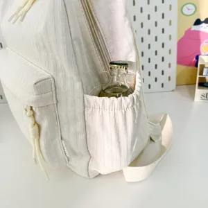 Gros plan détaillé d'un sac à dos blanc minimaliste et décontracté avec poche latérale et cordon.