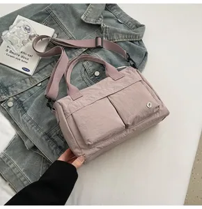 Λεπτομερής λήψη μιας casual μοβ νάιλον τσάντας χιαστί με διπλές τσέπες και ρυθμιζόμενο λουρί.
