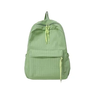 Détail de sac à dos étudiant vert montrant la texture du tissu, la poche avant et les zips.