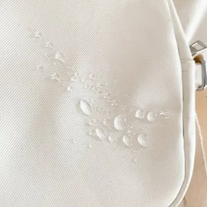 Détail de sac bandoulière en toile imperméable montrant texture résistante et imperméabilité.