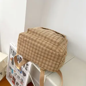 Λεπτομέρεια καφέ καρό σακιδίου πλάτης από κορδuroy με καθημερινό casual στυλ.