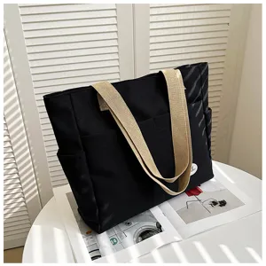 Black canvas tote bag detail view, casual daily shoulder handbag with wide khaki straps.