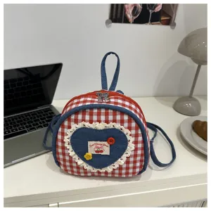 Vue détaillée du sac à dos en denim vichy rouge et blanc avec écusson cœur, dentelle et broderie.