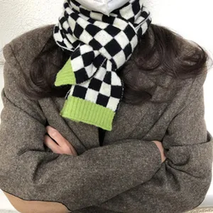Schwarz-weißer Karo-Strickschal mit grünen Enden, kuscheliges Winter-Modeaccessoire.