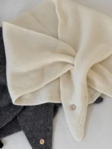 Detailansicht des weichen Woll-Minischals mit schickem Lochmuster und Metall-Anhänger.