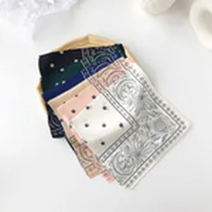Detail view of stylish small silk scarf featuring chic polka dot and vintage patterns.