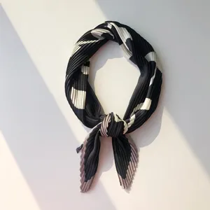 Detailed shot of pleated small scarf showing black and white geometric pattern texture.