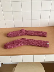 Detailaufnahme von dicken Wollmischung Stricksocken in roter melierter Optik flach.