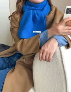 Primer plano de bufanda de punto azul brillante de invierno con abrigo elegante.