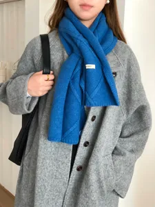 Vista detallada de una elegante bufanda de punto azul con diseño de cruz de botones en invierno.