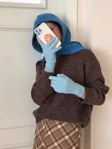 Detail shot of cozy blue knit balaclava hood and light blue gloves, soft winter warm style.