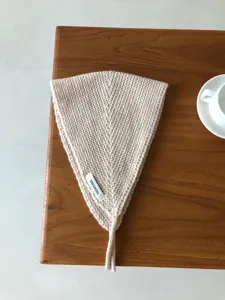 Nahaufnahme eines kuscheligen beigen Strick-Ohrwärmers aus Wolle auf einem Holztisch.