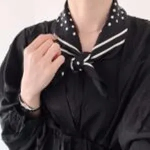 Nahaufnahme eines eleganten schwarzen Seidenschals mit weißen Punkten und Streifenmuster.
