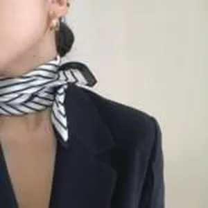 Detail view of a chic black and white striped silk scarf worn elegantly around the neck.