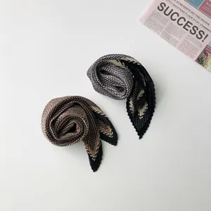 Pleated small square scarf with retro geometric pattern, chic silk scarf closeup.