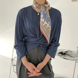 Detail shot of a stylish printed silk square scarf worn around the neck with elegant drape.