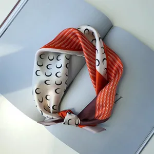 Nahaufnahme eines luxuriösen Seiden-Quadratschopfs mit ikonischem Halbmond-Druck und schickem Design.