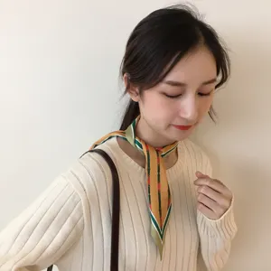 Gros plan détaillé d'un foulard en soie élégant avec motif géométrique porté par le modèle.