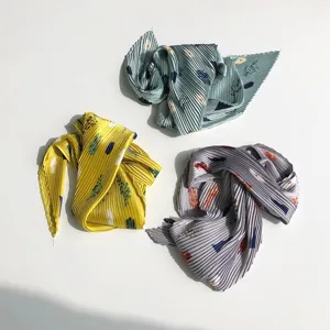 Detailed view of three pleated small square scarves in yellow, green, and grey colors.