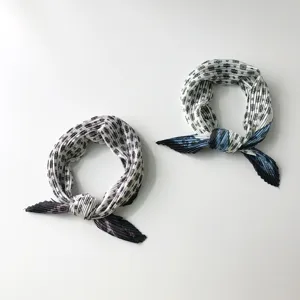 Detailed view of vintage pleated small neck scarf, delicate folds and retro print.