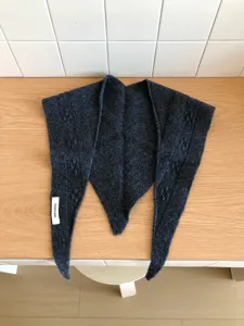 Detailed view of the dark grey wool knit triangular scarf, showing soft texture and cozy wear.