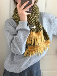 Detailed view of the soft yellow and black plaid winter scarf with cozy fringe and brand tag.