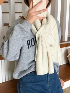 Vista detallada de una acogedora bufanda de punto beige con diseño de botones para el invierno.