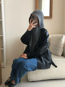 Detailed shot of grey knit balaclava hood scarf styled with black leather jacket for winter outfit.