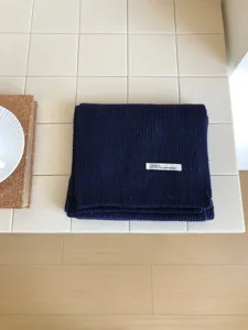 Vista detallada de una bufanda de invierno de punto azul oscuro, lana suave, diseño elegante.