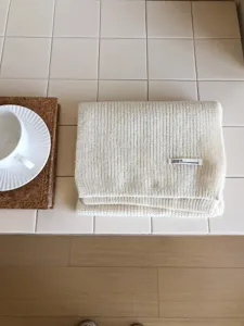 Primer plano de una suave bufanda de invierno tejida doblada sobre limpias baldosas.