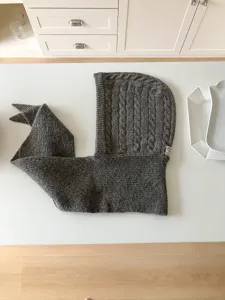 Detail view of the dark grey knitted balaclava hooded scarf, showing the cable knit texture.