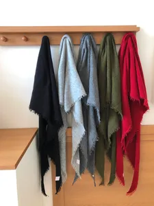 Close-up detail of multi-color wool blend triangular scarves hanging neatly on wooden wall rack.