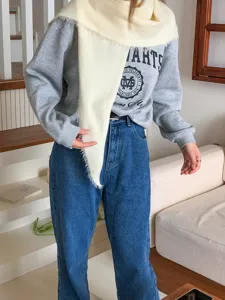 Cozy winter triangular wool scarf paired with casual grey collegiate sweatshirt and denim jeans.