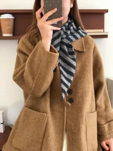 Detailaufnahme des grauen und schwarzen gestreiften Wolltuch-Dreiecks im eleganten Mantel-Look.