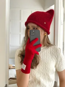Vue détaillée de gants d'hiver tricotés rouges confortables avec étiquette et bonnet assorti.