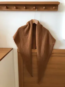 Detailed close-up view of the cozy brown wool blend triangular scarf on wooden hook.