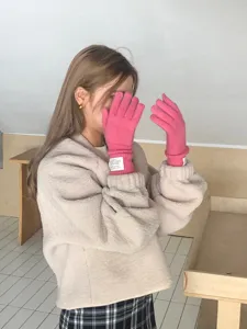 Gros plan détaillé de gants en laine tricotée rose vif portés par le modèle, poignets.