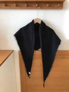 Detailed close-up shot of a black wool-blend triangular scarf featuring stylish fringe edges.