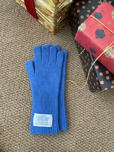 Gros plan détaillé de gants en tricot de laine bleue sur un tapis avec des boîtes cadeaux festives.
